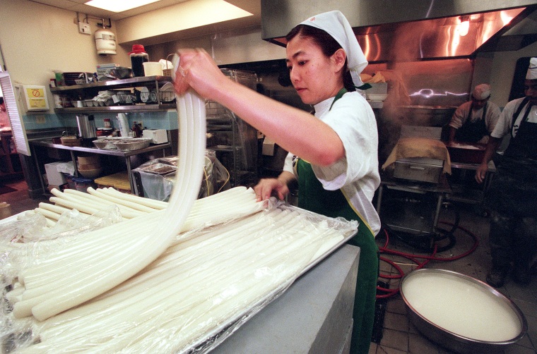 Yumi Yang pulls tteokbokki rice cakes apart before they are chopped up at San Su Jang rice cake shop in Los Angeles